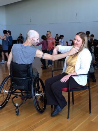 kelsey, seated, dancing with a man in a wheelchair