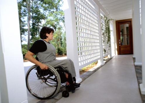 A wheelchair user crosses the threshold of her house