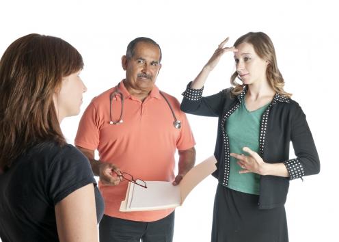 A man with a stethoscope and two women using sign language